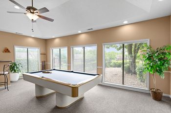 A pool table in a room with a ceiling fan and sliding glass doors.