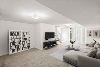 A living room with a grey couch, a television, and a bookshelf.