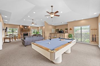 A pool table is in the middle of a room with a ceiling fan.