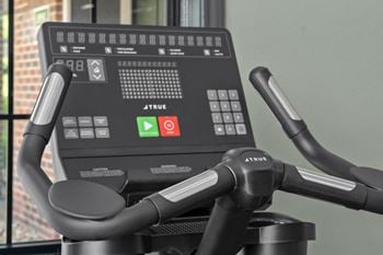 A close up of a true bike workout machine with a digital screen and handlebars.