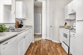 A white kitchen with wood floors and white appliances.
