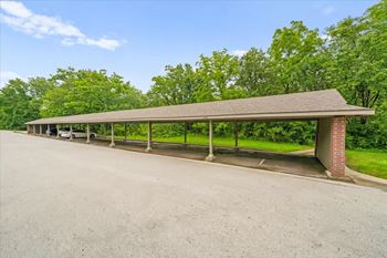 A long covered parking area with a brick pillar.