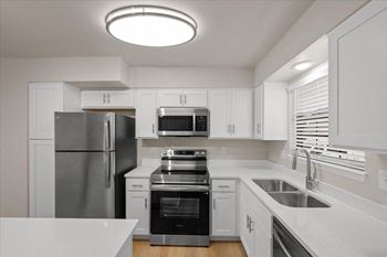 A modern kitchen with white cabinets and stainless steel appliances.