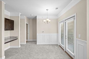 A dining room with white cabinets and a window and a door