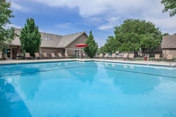 A swimming pool with lounge seating and trees 