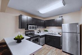 Overland Park apartment for rent - A kitchen with stainless steel appliances, black storage cabinets, and lots of counterspace at Preston Court Apartment Homes, Overland Park, Kansas