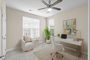 An office with a desk and a chair and a ceiling fan