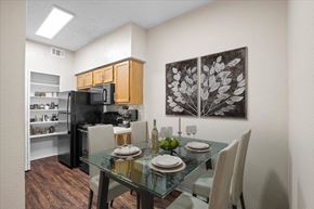 Dallas apartment for rent - a dining area with a glass table and chairs and a kitchen in the background at Creekview Apartment Homes, Texas