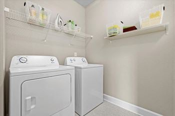 A white washer and dryer in a laundry room with shelves