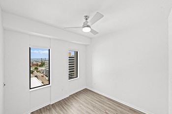 An empty living room with a window and a ceiling fan