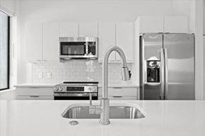 Kansas City apartment for rent - A modern kitchen with a stainless steel refrigerator and a sink at Sky On Main Apartments, Missouri City