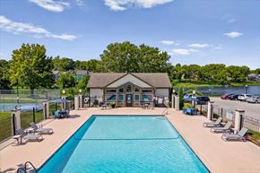 Olathe apartment for rent - Outdoor swimming pool with lounge seating and lake views at Millcreek Woods Apartment Homes.
