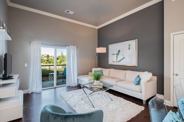 Overland Park apartment for rent - A living room with a white couch, a glass coffee table, and a painting on the wall.