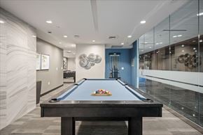 Kansas City apartment for rent - Resident game room at Sky on Main featuring a pool table, modern décor, and access to adjacent community spaces.