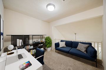 Overland Park apartment for rent - A blue couch sits in a living room with a white table and a plant.