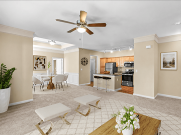 Olathe apartment for rent - A living room with a ceiling fan and a dining table with chairs.
