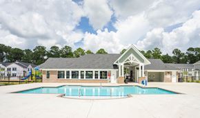 Bluffton apartment for rent - A pool area with a building and a slide in the background.