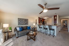 Hampton apartment for rent - Living room with a grey couch, a coffee table, and a ceiling fan at Mill Creek Landing near Newport News, VA