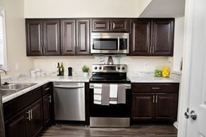 Raleigh townhouse for rent - A kitchen with dark brown cabinets and a black stove top oven.