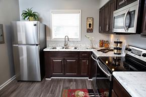 Mooresville apartment for rent - A kitchen with a stainless steel refrigerator and dark brown cabinets.