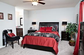Mooresville apartment for rent - A bedroom with a red bedspread and a black chair.