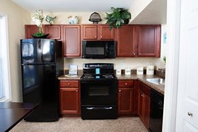 Fayetteville apartment for rent - a kitchen with dark wood cabinets and black appliances
