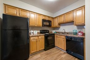 Virginia Beach townhouse for rent - A black refrigerator stands in a kitchen with wooden cabinets and black appliances.