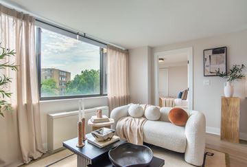 Washington apartment for rent - A living room with a white couch and a large window with curtains.