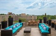 Washington apartment for rent - A patio with blue couches and a table surrounded by black speakers.