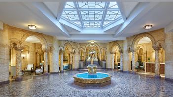 Grand reception lobby with statuary fountain, scagliola columns, and dramatic skylight