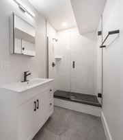 Washington apartment for rent - A white bathroom with a sink, mirror, and walk-in shower.