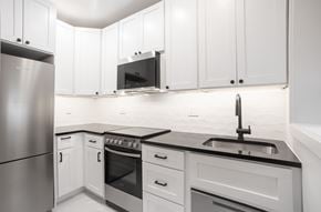 Washington apartment for rent - A modern kitchen with white cabinets and stainless steel appliances.