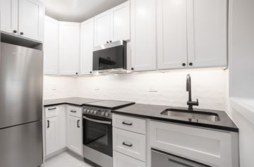 Washington apartment for rent - A modern kitchen with white cabinets and stainless steel appliances.