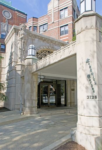 Elegant porte cochere covered entry with carved limestone reliefs and original art deco lighting fixtures,