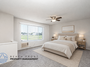 Anaheim apartment for rent - A bedroom with a large bed, a window with a view of the beach, and a ceiling fan.
