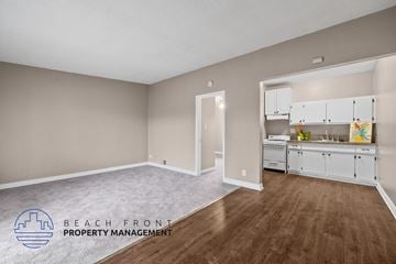 Downey apartment for rent - a living room and kitchen with white cabinets and wood flooring
