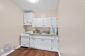 Downey apartment for rent - a kitchen with white cabinets and a sink and a stove