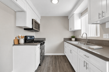 Hawthorne apartment for rent - A kitchen with white cabinets and a black stove top oven.