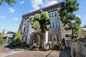 Los Angeles apartment for rent - a gray building with a gate and trees in front of it