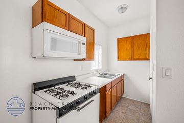 Long Beach apartment for rent - a kitchen with a stove and a microwave and wooden cabinets