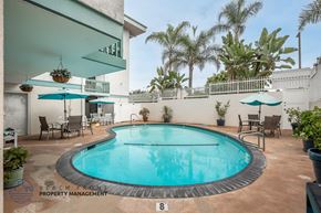 Long Beach apartment for rent - A pool surrounded by chairs and umbrellas with a sign that says