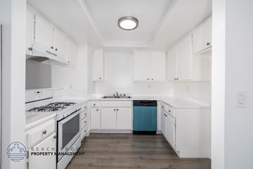 Hawthorne apartment for rent - A kitchen with white cabinets and a blue trash can.