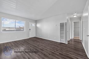 Long Beach apartment for rent - A spacious room with wooden flooring and a large window overlooking a beach.