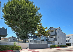 Paramount apartment for rent - A large grey building with a tree in front of it.