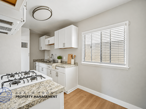 Hawthorne apartment for rent - A kitchen with a white stove top oven and white cabinets.