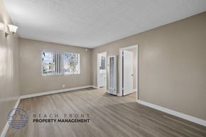 Hawthorne apartment for rent - A spacious room with wooden flooring and a refrigerator in the corner.