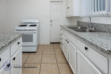 Long Beach apartment for rent - A kitchen with white cabinets and a granite countertop.
