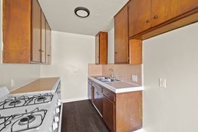 Inglewood apartment for rent - A kitchen with a stove top oven and wooden cabinets.