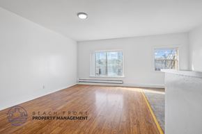 Los Angeles apartment for rent - A room with wooden flooring and two windows, one of which has a view of a construction site.