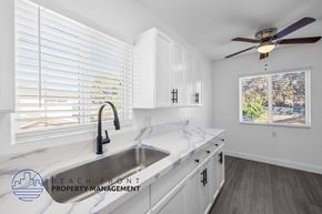 Signal Hill apartment for rent - A kitchen with a marble countertop and a view of the city through the window.